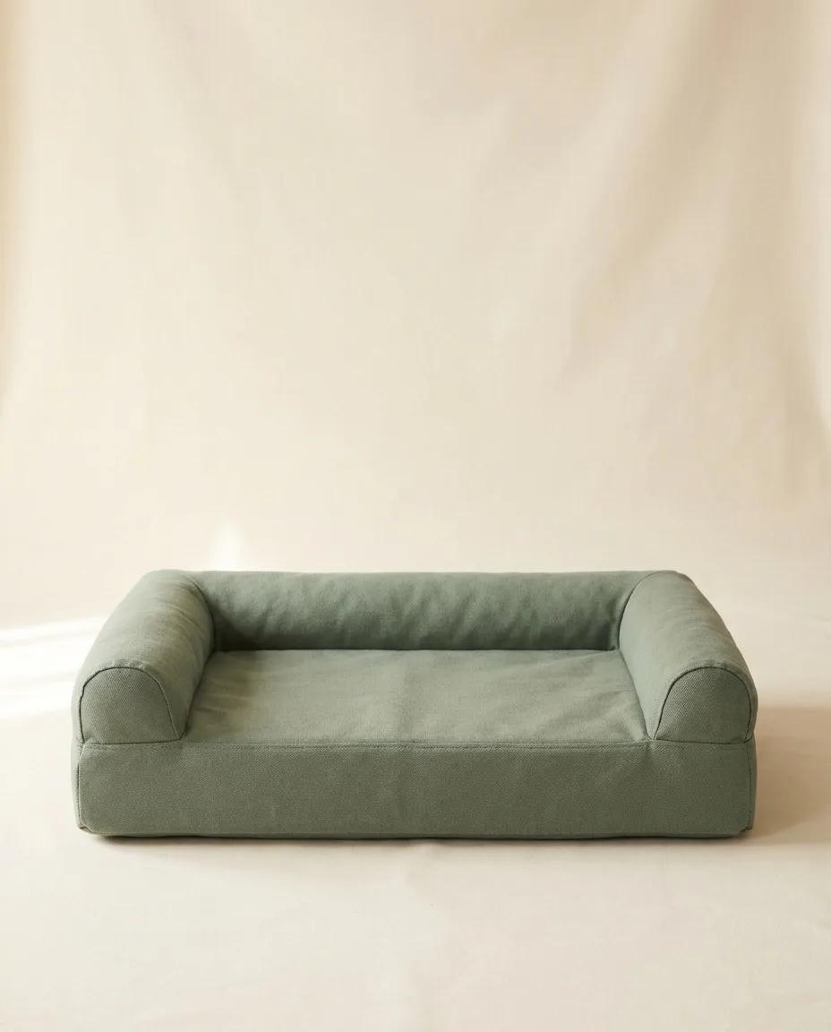 A sage-green mattress dog bed with bolsters